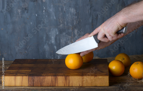 Chef Slicing Fresh Oranges on Wooden Board