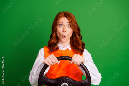 фотографія Surprised female driver gripping steering wheel against green background — redhe