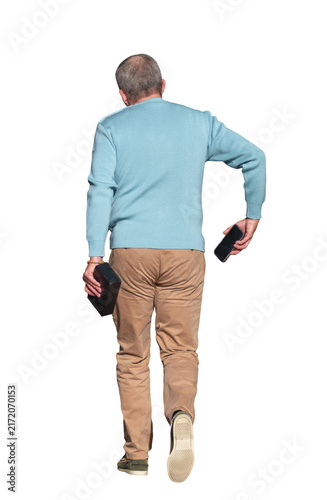 Foto Homme adulte vu de dos marchant avec un smartphone  qu'il s'apprête à mettre dan