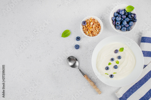 Konstfotografi Bowl of creamy yogurt topped with fresh blueberries and mint leaves, accompanied