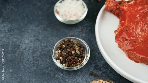 Raw meat preparation with spices and coarse salt on a dark background