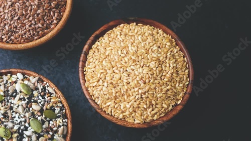 Three wooden bowls filled with assorted seeds against a dark background