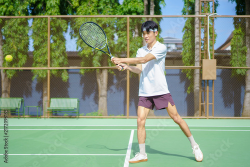 Cuadro en lienzo Focused young Asian male tennis player executing a backhand stroke on an outdoor