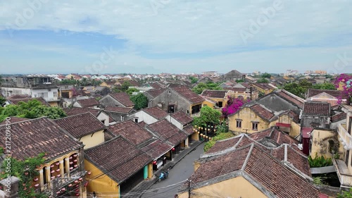 Panoramic high-angle view of red tiled roofs and yellow ancient buildings in Hoi An under a bright sky