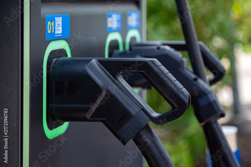 An electric car charging station is shown with connectors ready for use in a city space.