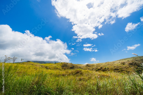 Serene rural landscape featuring lush green grass and rolling hills beneath a clear blue sky. A peaceful nature scene at the Batu Angus tourist area in Bitung, Indonesia.