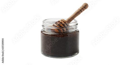 Foto Glass jar with dark body scrub and wooden honey dipper