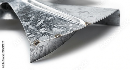 Macro of a commercial HVAC centrifugal blower fan blade trailing edge. Heavy galvanized steel airfoil with raw metallic texture and spot welds for industrial air handling hardware.