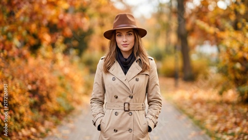 Beautiful Young Woman Wearing Trench Coat and Fedora Hat in Autumn Park