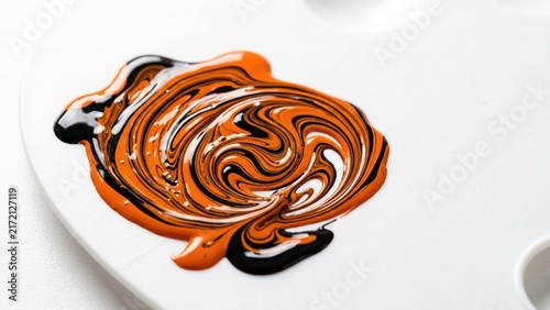 Abstract Swirl of Orange and Black Paint on an Artist Palette