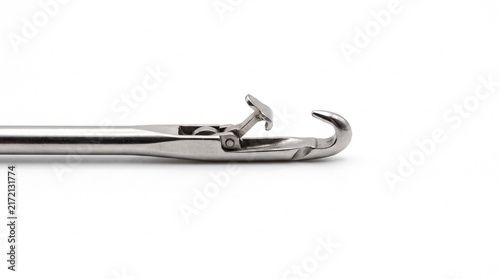 Macro of a steel circular knitting machine latch needle. Micro-machined pivoting hook mechanism for fabric production, isolated on white.