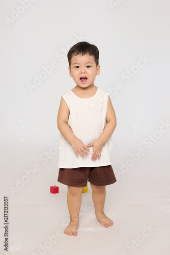 A 3-year-old toddler standing in a basic pose, wearing brown shorts and a white short-sleeved shirt.