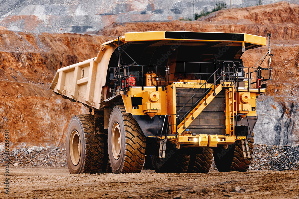 Obraz premium Front view large yellow mining dump truck at quarry edge for industrial banner and heavy equipment background