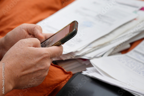 Hands typing on smartphone managing paper documents