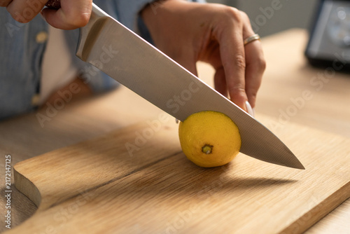 Картината върху платно Close-up of woman slicing lemon on cutting board.