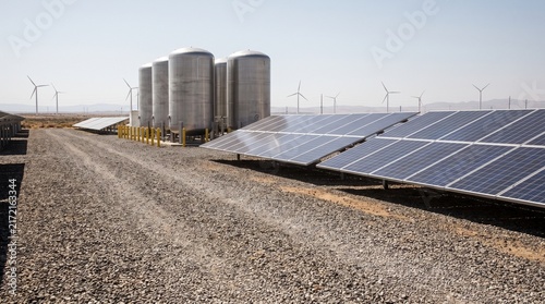Solar panels and grain silos in a rural agricultural landscape.