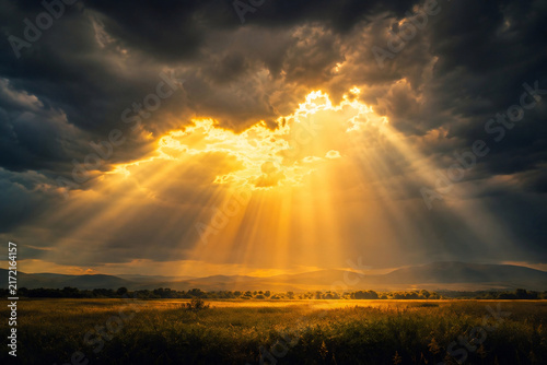 Dramatic Golden Sun Rays Breaking Through Dark Storm Clouds over Countryside