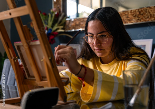 Fotografía Young woman concentrating on painting canvas on easel