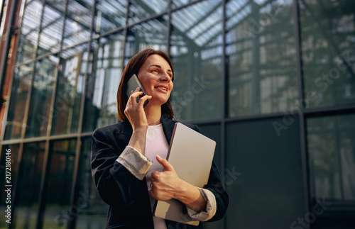 Businesswoman on a mobile phone by a glass office facade