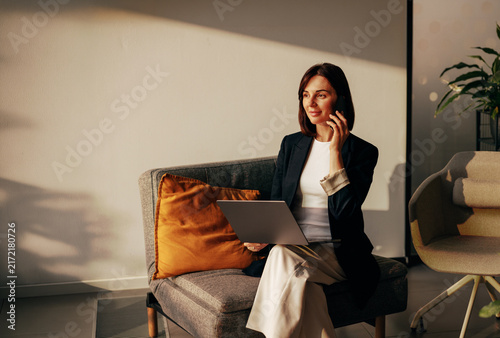 Businesswoman on a phone call with a laptop on a sofa