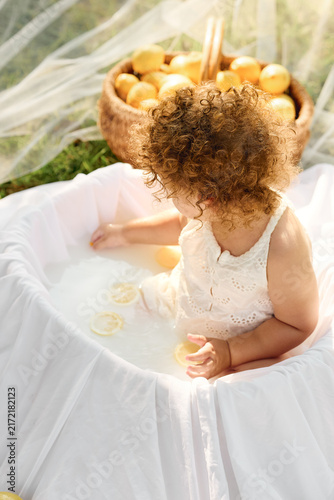     Curly toddler girl holding a lemon during a sunny outdoor photo session