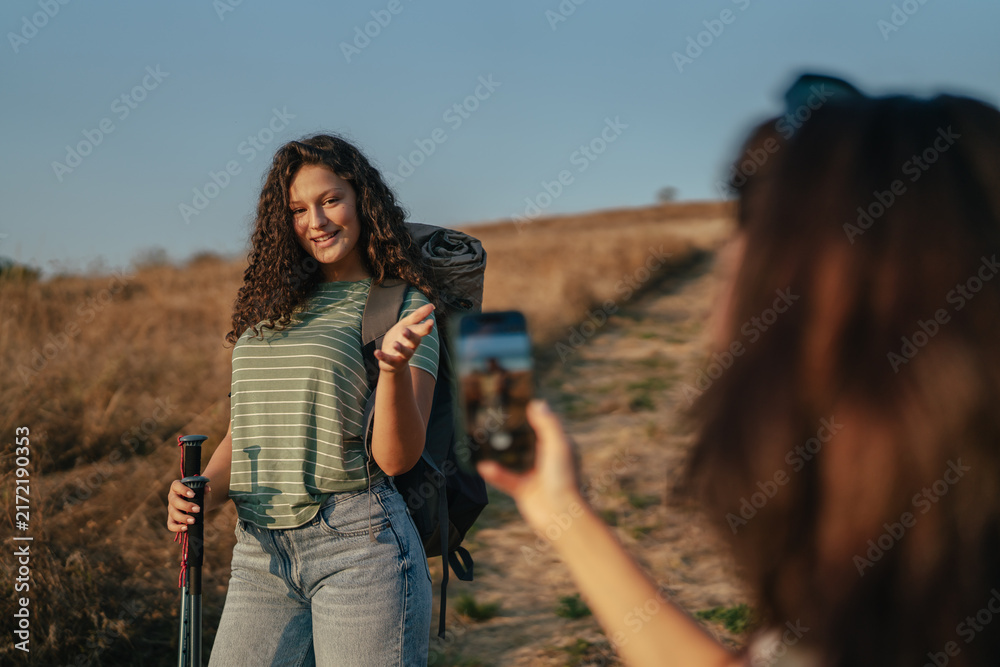 Naklejka premium Friends hiking and taking smartphone photos outdoors