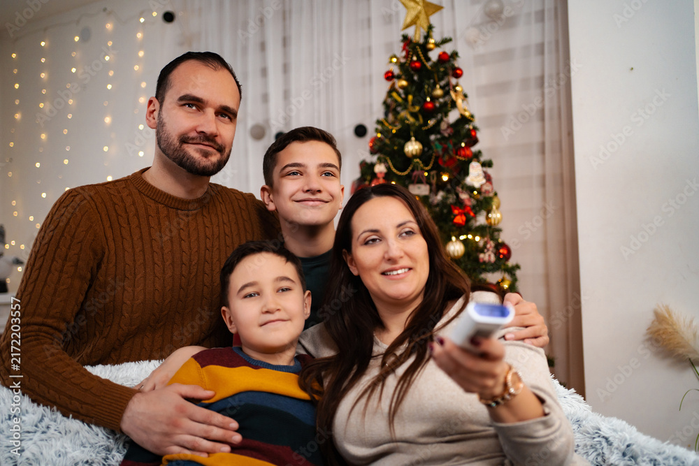 Obraz premium Family enjoying Christmas Eve at home, mom holding TV remote control