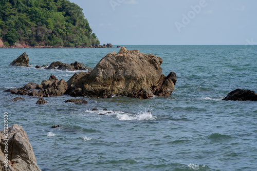 Rugged coastal rock formation surrounded by rolling seawater along a tropical shoreline in Thailand. Natural erosion, geology and an unspoiled marine landscape. Travel and coastal environment themes.
