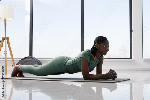Woman performing a plank exercise on a yoga mat in a bright, modern room