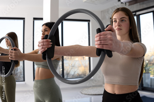 Women exercising with Pilates rings in a bright, modern studio setting