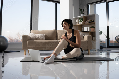 Woman using laptop for online fitness class at home