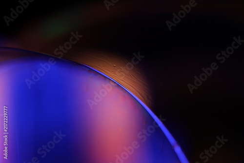 Glowing cobalt fluid membrane dome with sharp rim and warm amber halo. A smooth liquid membrane dome is illuminated in deep cobalt blue and soft purple gradients in low-key macro perspect