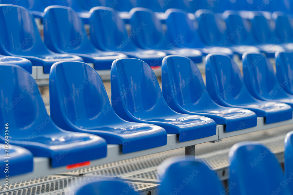Obraz premium Vibrant blue bleacher seats stand ready for cheering crowds during an exciting sports event at a bustling stadium