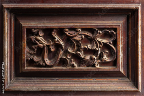 Ornate antique carved wood panel featuring intricate floral scrollwork in framed bas-relief, showcasing rich patina, detailed craftsmanship and vintage decorative style for interior design