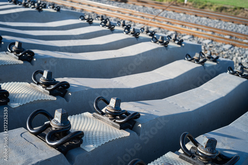 Foto Close-up view of railway track concrete sleepers with metal fasteners and bolts