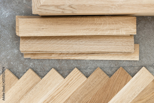 Beige parquet planks on concrete floor during herringbone hardwood flooring installation