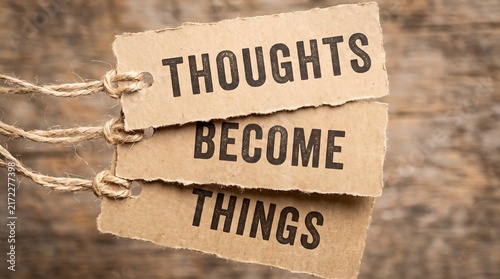 Inspirational thoughts become things message on cardboard tags. Rustic paper labels with motivational quote. Brown kraft paper signs on wood.