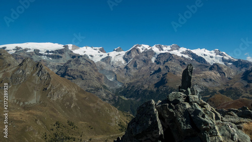 Stone cairn marker on Monte Facciabella peak with scenic view of Monte Rosa massif, Aosta Valley, Italy