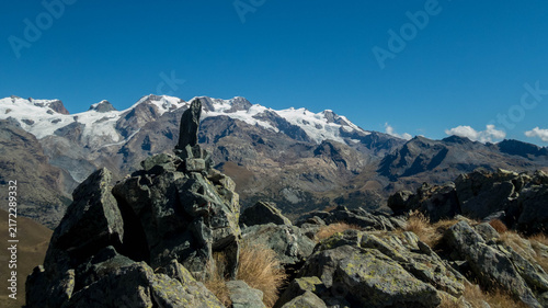 Stone cairn marker on Monte Facciabella peak with scenic view of Monte Rosa massif, Aosta Valley, Italy