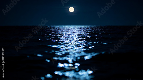 Moonlit horizon over calm ocean at night, full moon glowing sky nature background