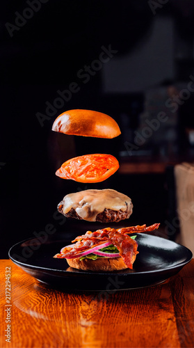 Obraz na plátně Hamburguer com bacon, queijo, tomate e cebola roxa, gravidade