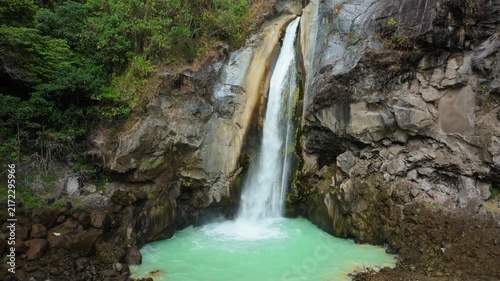 Aerial view of Mangku Sakti waterfall falling into turquoise sulfur pool in Rinjani rainforest Lombok
