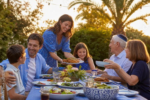 A Joyful Family Gathering Outdoors: A multi-generational family shares a celebratory meal under the warm evening sun, laughing and connecting around a table laden with food.