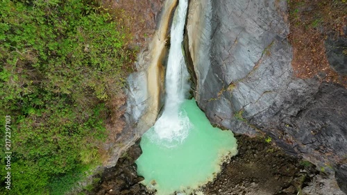 Top down aerial view of Mangku Sakti waterfall plunging into turquoise pool in rock gorge Lombok