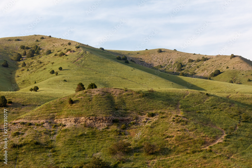 Fototapeta premium Rolling green hills under a soft blue sky