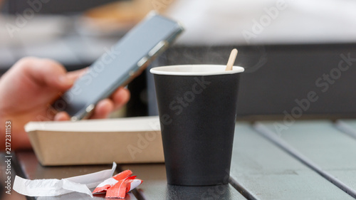 Bild auf Leinwand Hand holds phone beside coffee cup