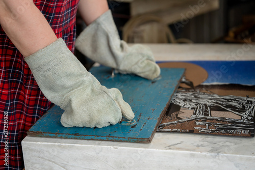 Принти на полотні Artisan in heat resistant protective gloves pressing hot handmade enamel metal plate with heavy slab on marble table to flatten and cool it during crafting