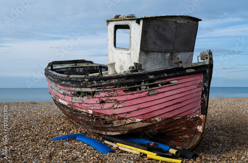 Foto Broken old fishing boat with severely deteriorated wooden hull and faded red pai