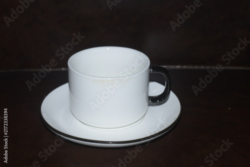 Konstfotografi White ceramic tea cup and saucer set on reflective dark wood table