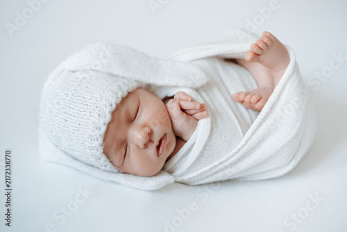 A newborn baby is sleeping in a diaper against a white, isolated background; space for text. The little baby is sleeping sweetly.